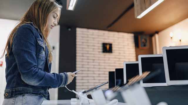 young-attractive-girl-electronics-store-stands-desk-tests-phone.jpg